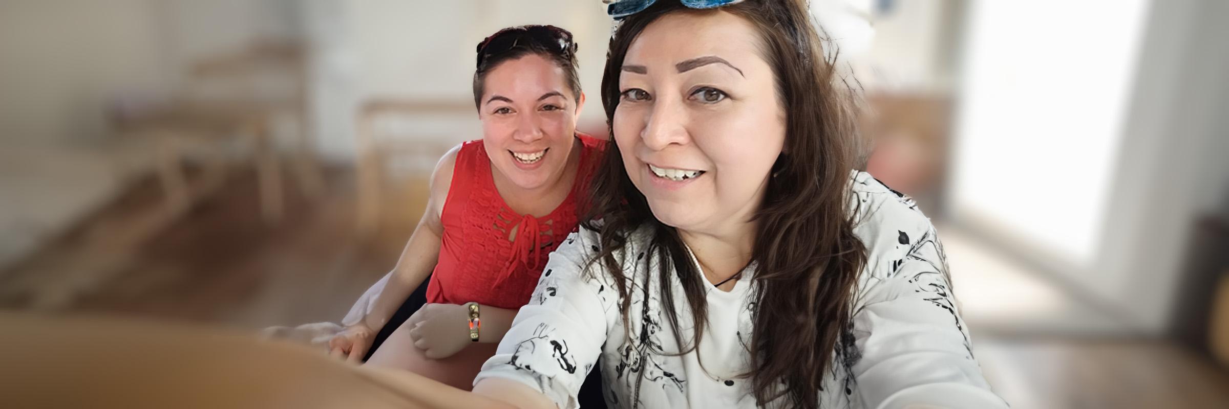 Photo of two Health Care Authority staff, Jennifer (left) and Melissa (right), taking a self-portrait photo indoors. 