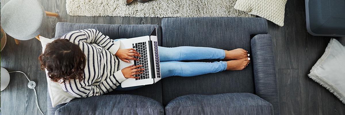 Overview of person on couch using a laptop.