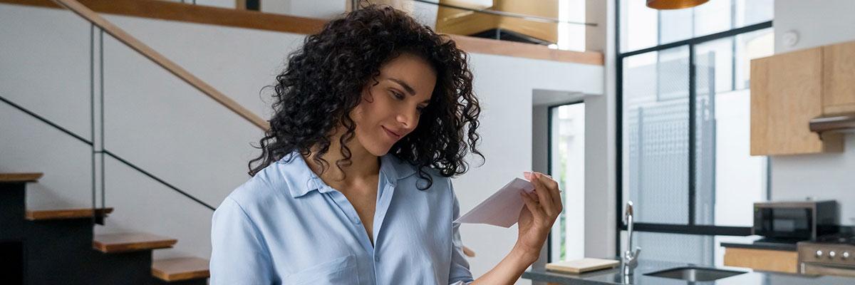 Woman standing at kitchen counter looking at mail