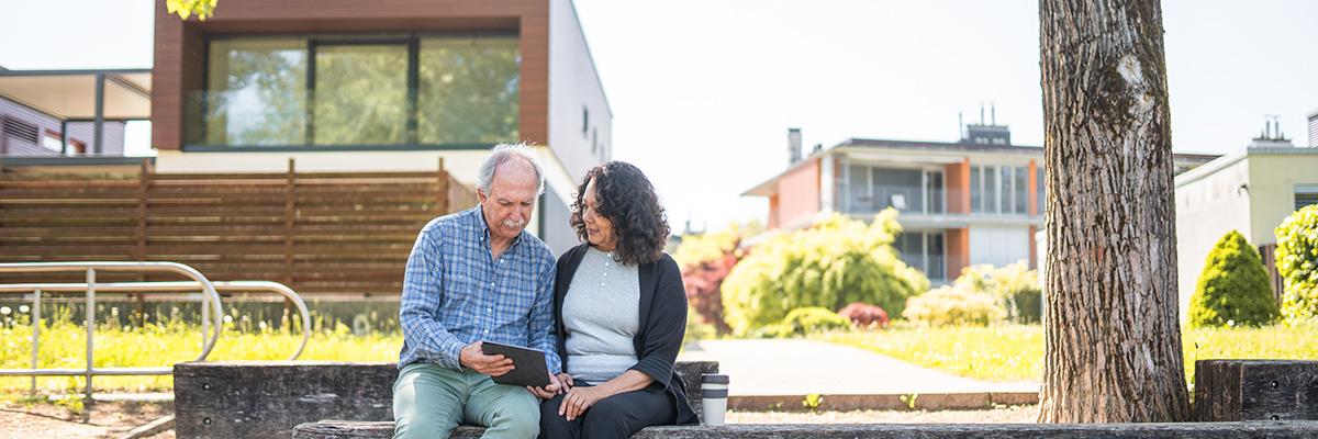 Senior man and woman looking at tablet in a suburban outside setting. 