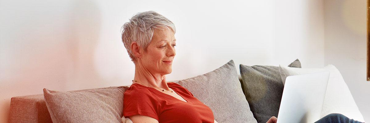 Older woman sitting on couch working on laptop