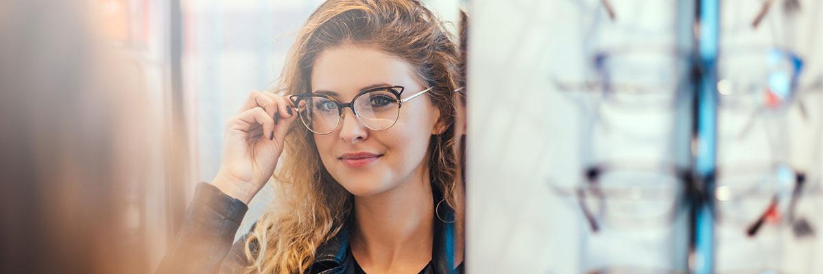 A woman looking in the mirror with eyeglasses on