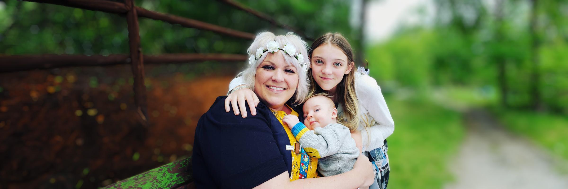 Photo of a mother holding her newborn baby with her daughter standing by her side. 