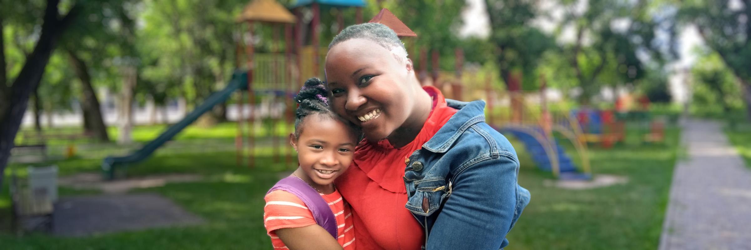 Outdoor photo of mother and young daughter at a park. 