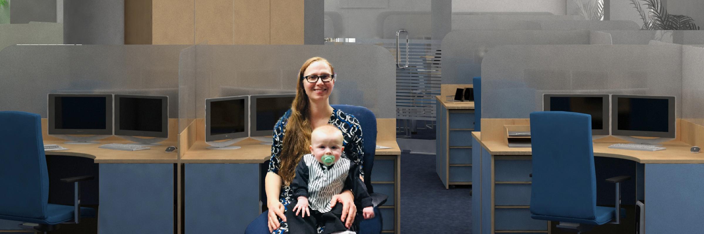 Stephanie Zier sitting a blue desk chair in front of a desk with her infant son, Finn, on her lap.
